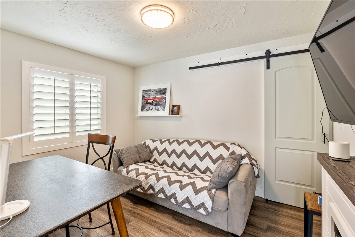 Room featuring wood-finish flooring and a white barn door on a black metal track