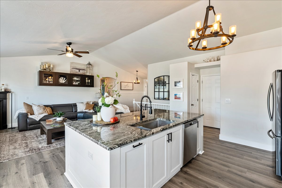 Kitchen island with a granite countertop, undermount sink, and white cabinetry