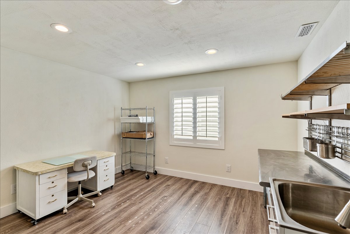 Room featuring wood-finish flooring, recessed lighting, and a window with plantation shutters