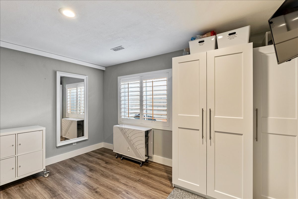 Room featuring wood-finish flooring, recessed lighting, and a window with white plantation shutters