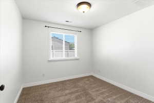 Carpeted room featuring a window with blinds, a ceiling-mounted light fixture, white walls, and white baseboards