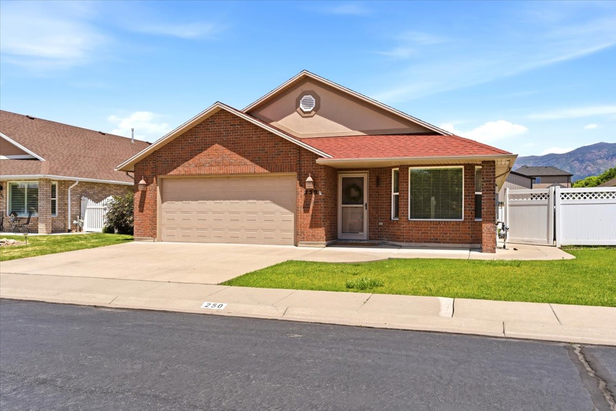 Brick exterior with a prominent two-car garage, red shingle roofing, and a front porch entry