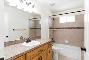 Bathroom featuring a light wood-finish vanity with a speckled countertop, an integrated sink, and bronze-finish fixtures