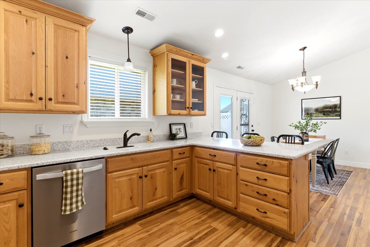 Kitchen with light wood cabinetry, light-toned countertops, and wood-finish flooring