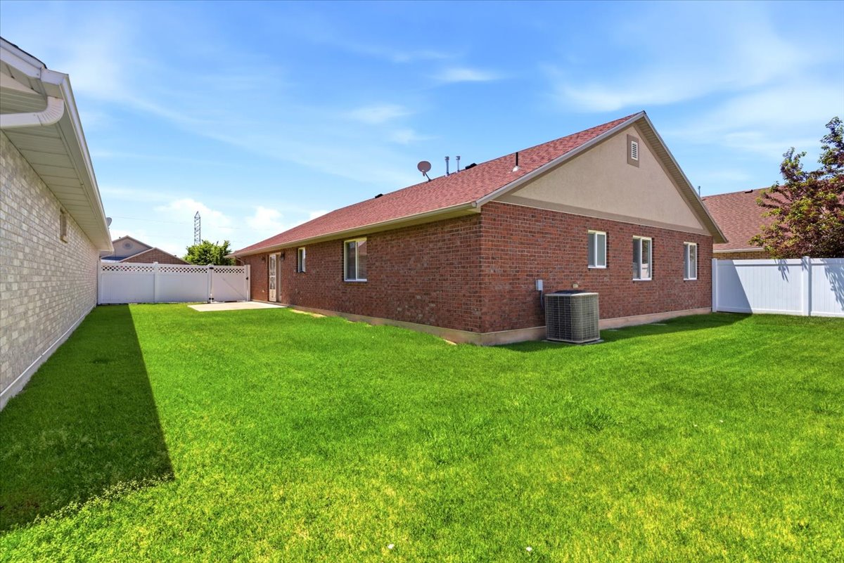 Expansive green lawn with a white vinyl fence and a brick-sided exterior