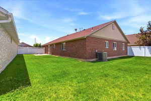 Expansive green lawn with a white vinyl fence and a brick-sided exterior