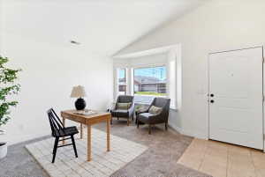 Entryway featuring a paneled door, tiled flooring, vaulted ceilings, and a bay window