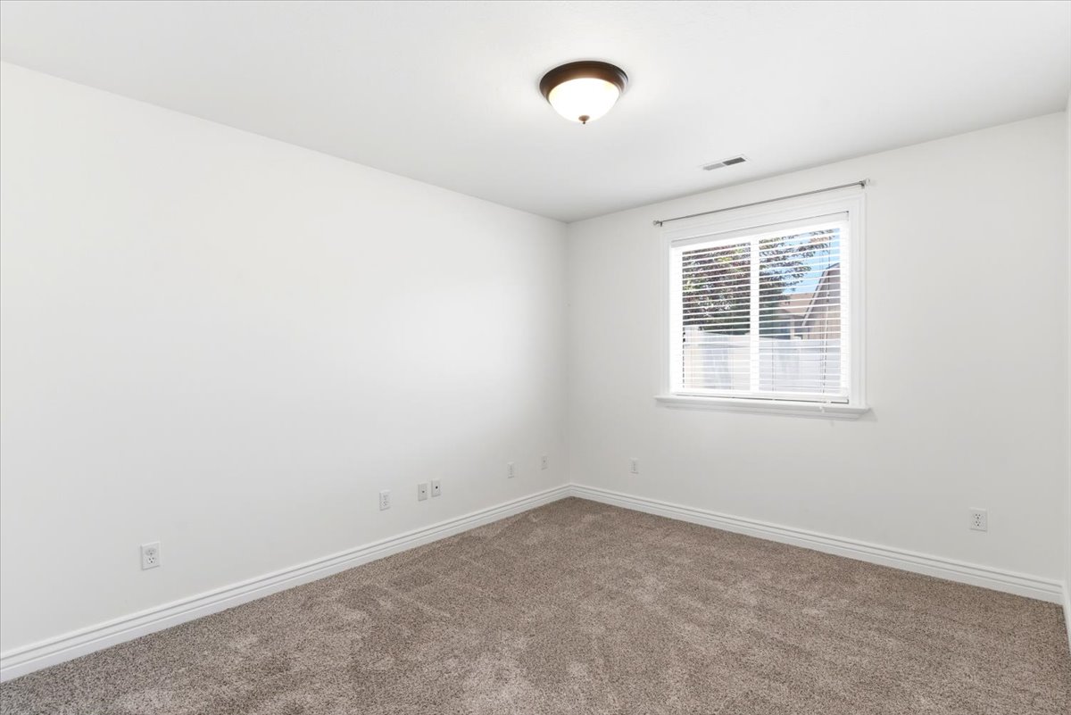 Carpeted room with a ceiling-mounted light fixture, a window with blinds, and white baseboards