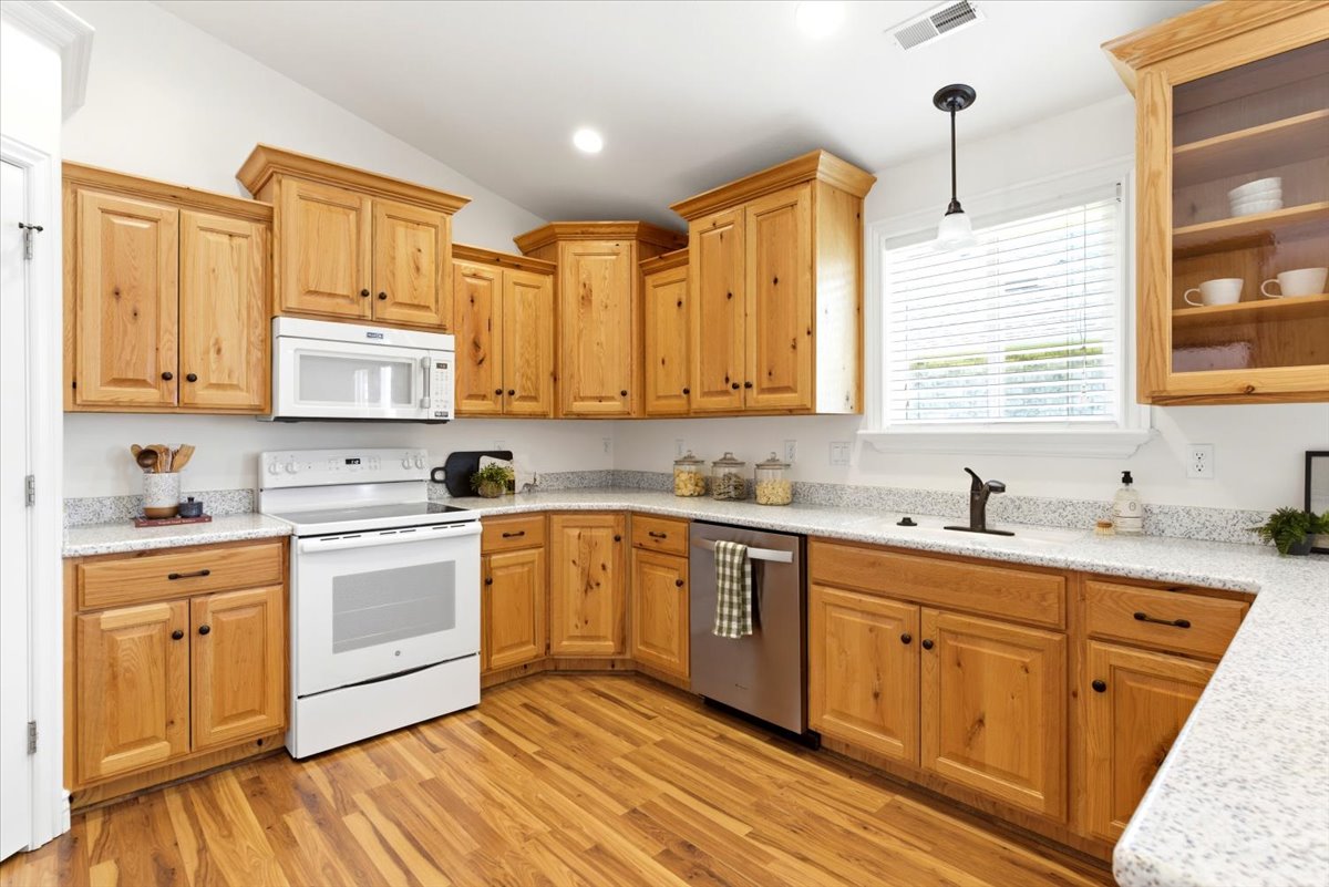 Kitchen featuring wood-finish cabinetry, solid surface countertops, and wood-finish flooring