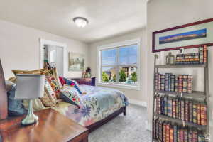 Bright bedroom featuring a large window, soft neutral wall paint, and a built-in closet with shelving