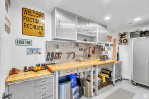Garage workspace featuring a light wood-finish countertop, metal cabinetry, and a pegboard storage system