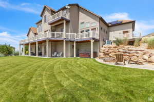 Multi-level rear exterior featuring stucco siding, multiple balconies with white railings, and a lower-level covered patio