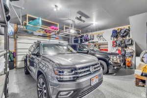 Two-car garage featuring epoxy flooring, overhead storage racks, built-in shelving, track lighting, and a paneled garage door