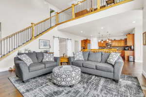 Living area featuring dark wood-finish flooring, a double-height ceiling, and a wooden staircase with black iron balusters