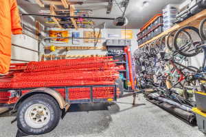 Garage interior featuring a speckled epoxy floor coating, overhead ski storage racks, wall-mounted bicycle storage, and built-in shelving