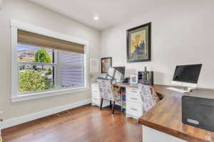 Room featuring wood-finish flooring, a large window with white trim, and light-toned walls