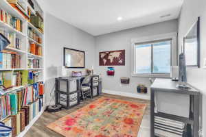 Built-in shelving, wood-finish flooring, recessed lighting, and a large window