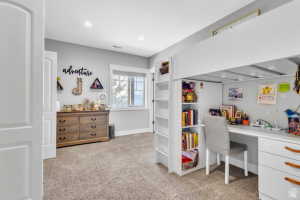Built-in loft bed with integrated desk and shelving, recessed lighting, neutral carpeting, light gray wall tones, and a window with white trim
