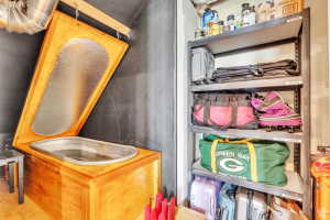 Built-in cold plunge with wood-finish surround, galvanized tub, and hinged lid, complemented by industrial-style metal shelving