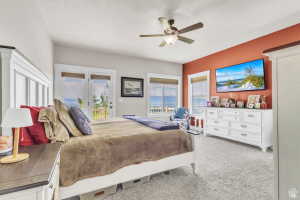 Spacious bedroom featuring light gray walls with an accent wall in terracotta, white trim throughout, and light gray carpeting