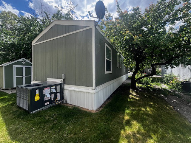 Exterior featuring green vertical siding, white trim, and a white skirting foundation