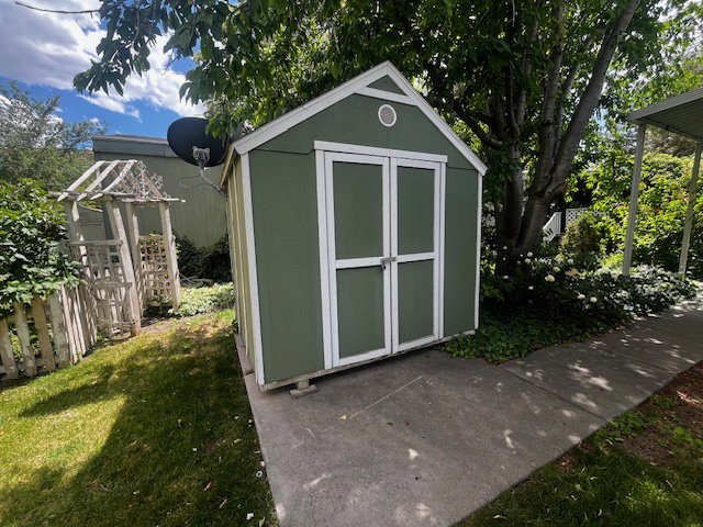 Green storage shed with white trim and double doors