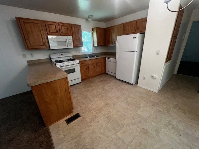 Kitchen featuring wood-finish cabinetry, laminate countertops, and tile-look flooring