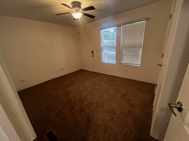 Spacious room featuring brown carpet flooring, light-toned walls, and a ceiling fan with integrated lighting