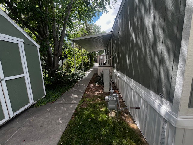 Exterior features a side walkway, an attached covered carport, and a detached storage shed
