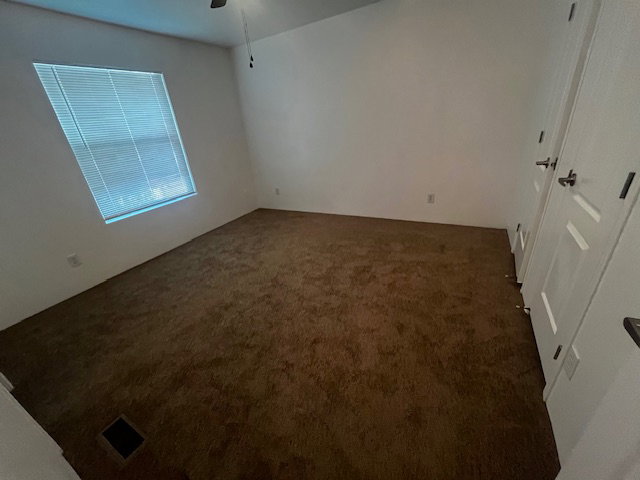 Carpeted room featuring a ceiling fan, a window with horizontal blinds, and a pair of white paneled doors with dark hardware