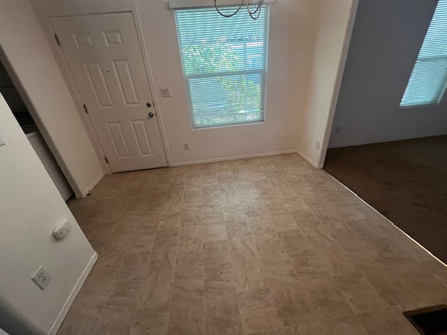 Entryway featuring tile-finish flooring, a paneled door, and a window with blinds