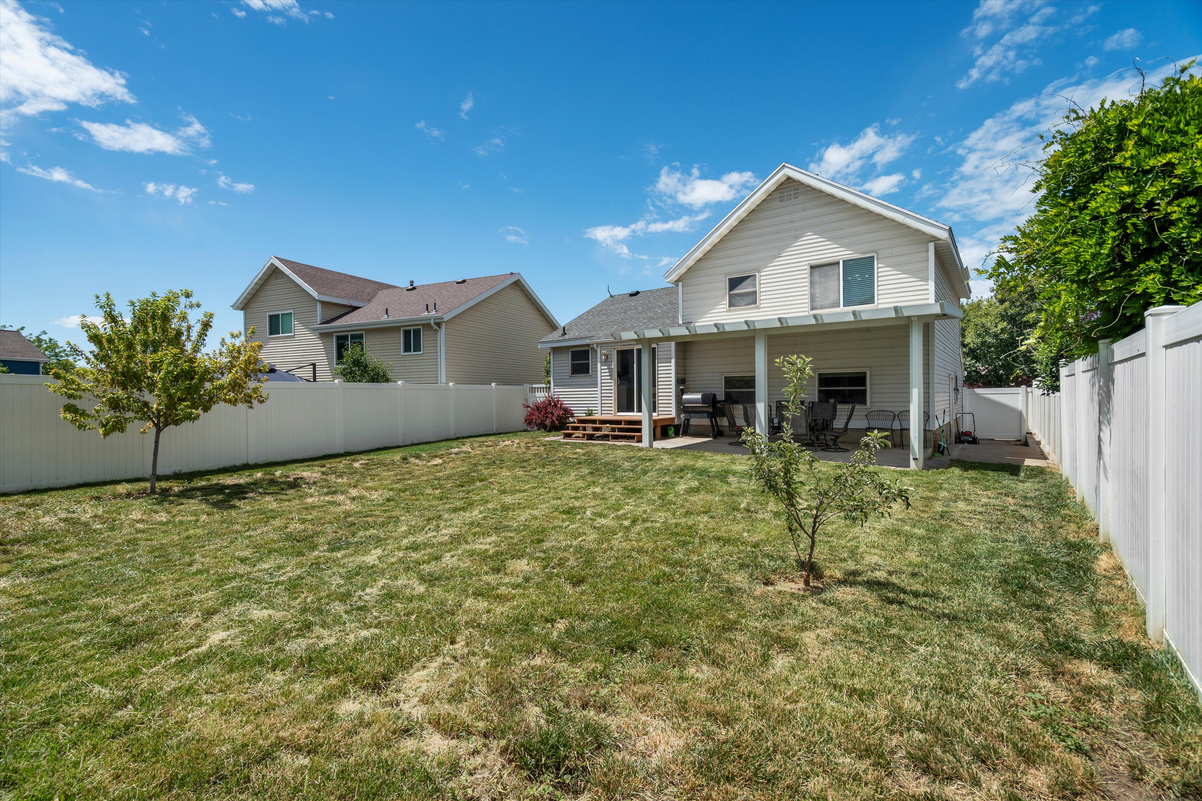 Expansive backyard featuring a pergola-covered patio, privacy fencing, and mature landscaping