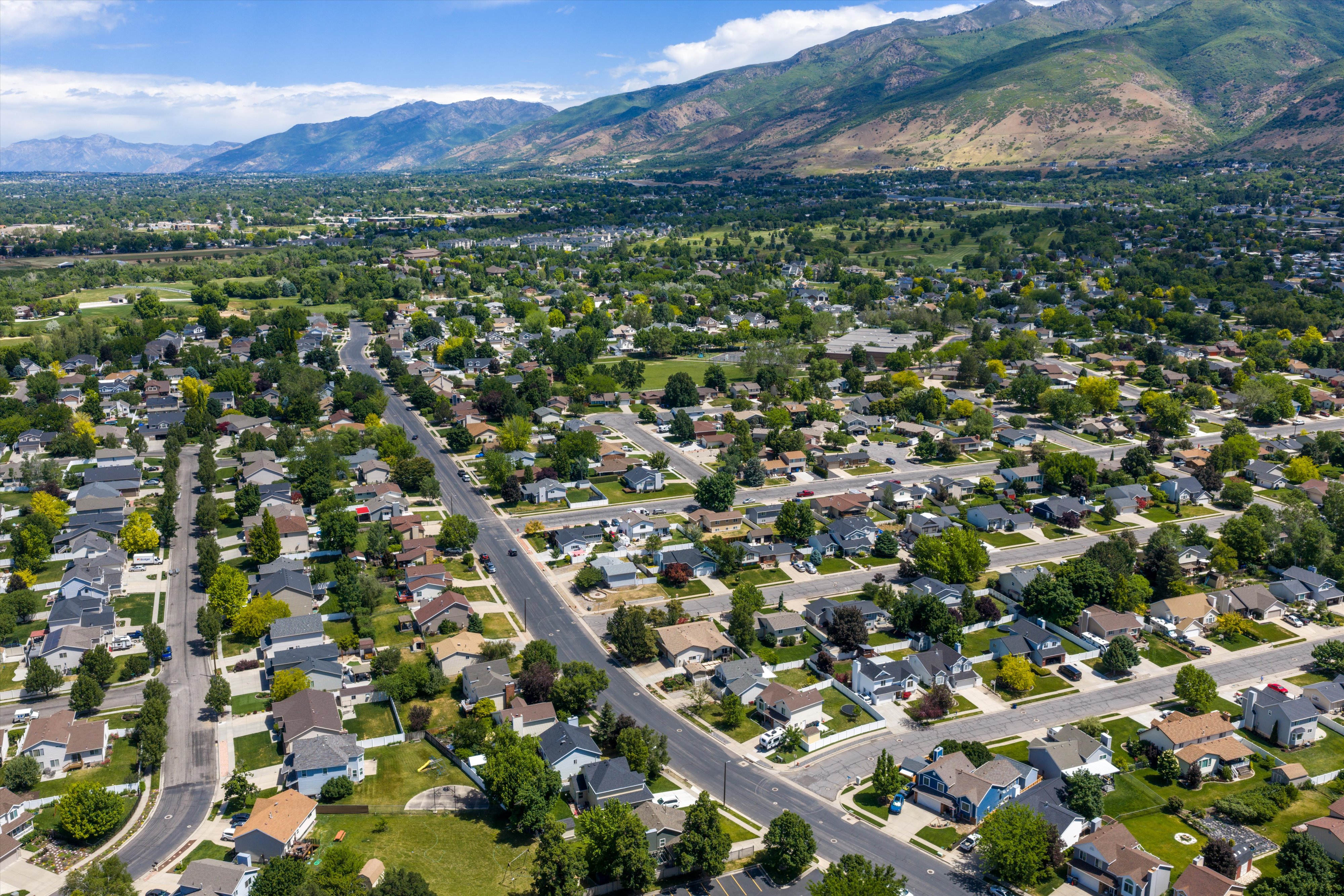 Expansive residential area featuring numerous single-family homes, mature tree-lined streets, and mountain ranges in the background