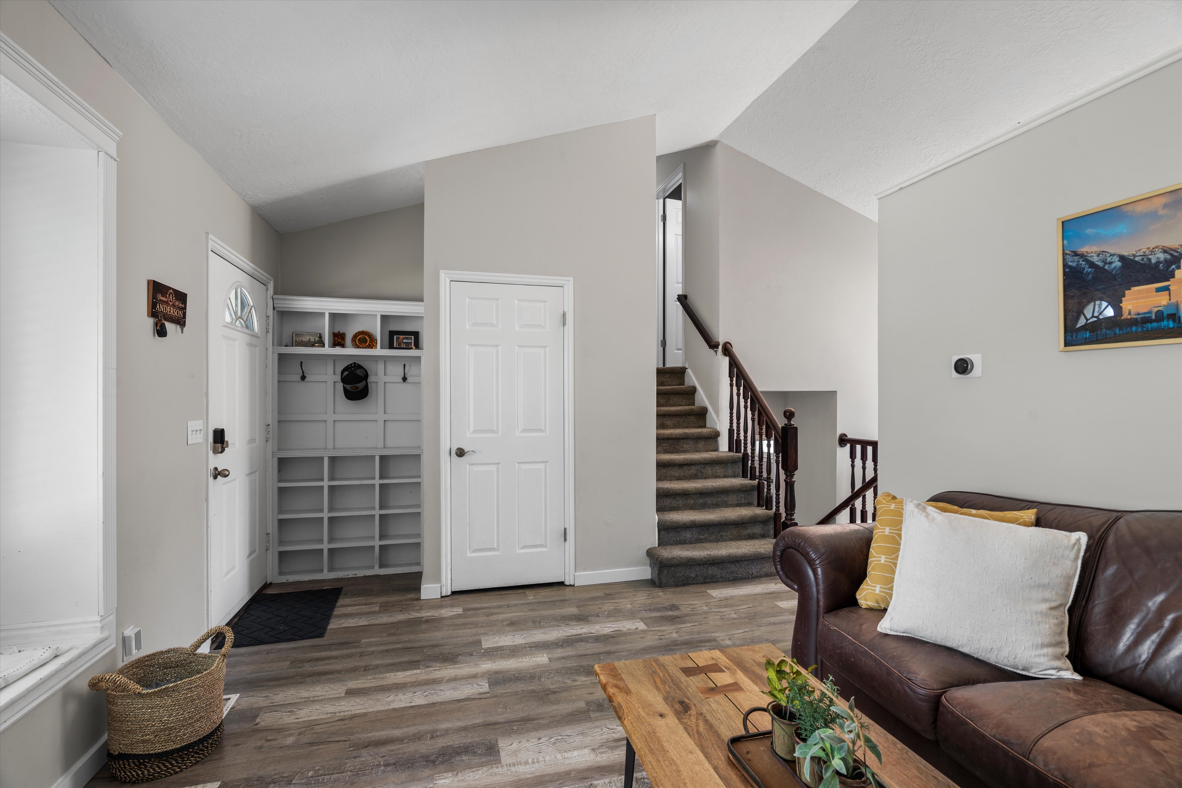 Entryway featuring wood-finish flooring, a white paneled entry door with decorative glass, and a built-in storage unit with shelving and hooks