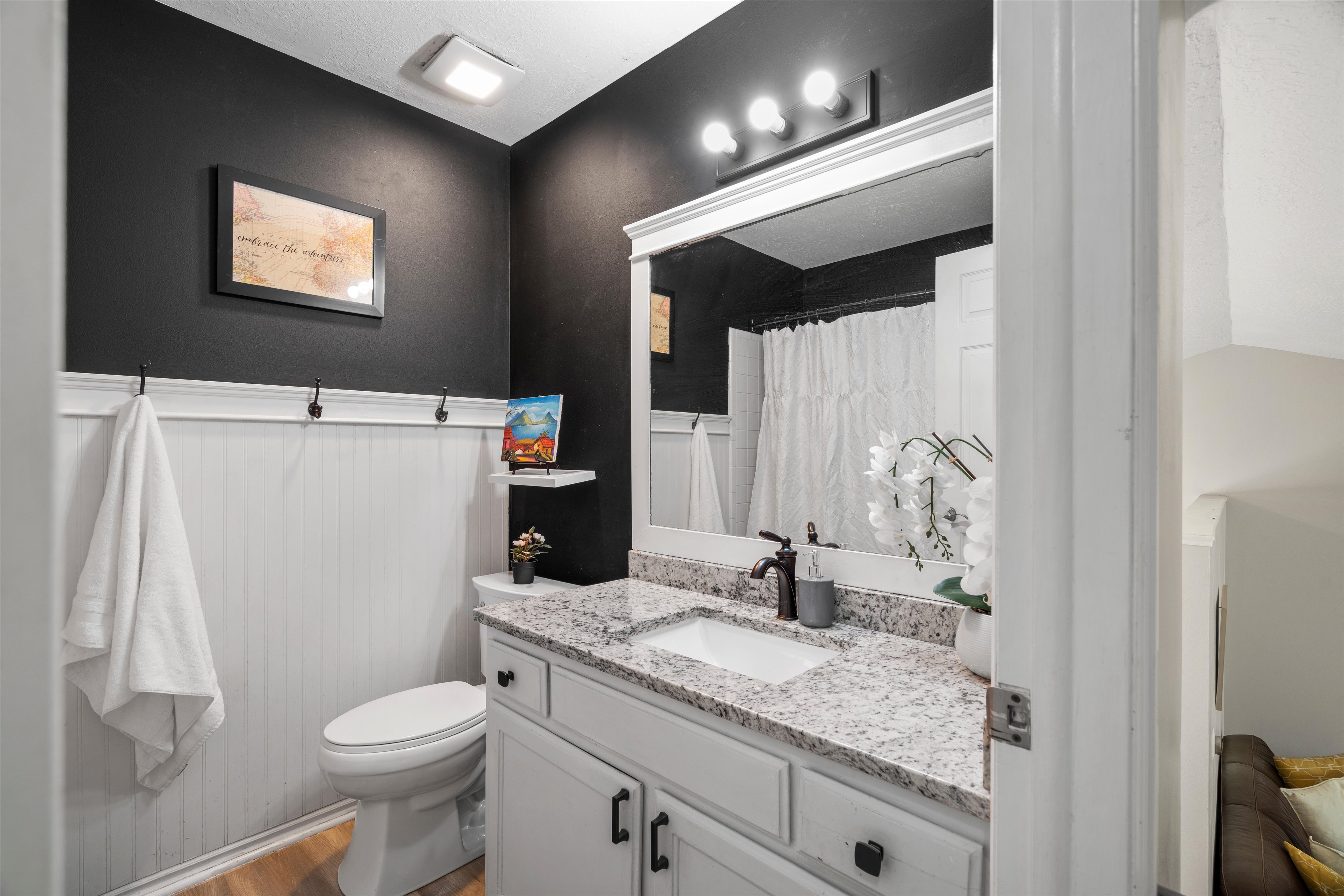 Bathroom featuring a white vanity with a rectangular sink, speckled countertop, and dark bronze faucet