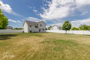 Expansive backyard featuring a large grass area, mature trees, and a full privacy fence