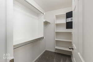 Walk-in closet featuring white built-in shelving, chrome hanging rods, and gray carpet flooring