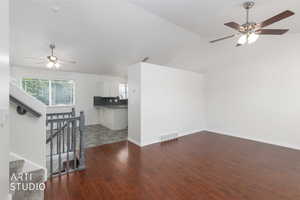 Spacious room featuring wood-finish flooring, vaulted ceiling, and a ceiling fan with integrated lighting
