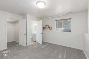 Carpeted room featuring a window with blinds, a walk-in closet
