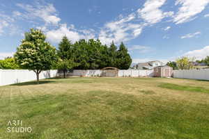 Spacious backyard featuring a manicured lawn, mature trees, and privacy fencing