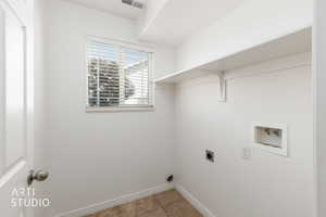 Dedicated laundry area featuring a window with horizontal blinds, overhead shelving, white walls, and neutral-toned tile flooring