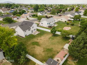 Expansive backyard featuring a large lawn area, mature perimeter trees, and a white privacy fence