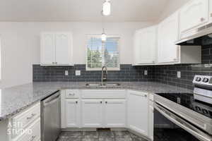 Kitchen featuring white cabinetry, granite-finish countertops, subway tile backsplash, stainless steel appliances, and a window with blinds