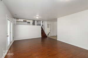 Spacious room featuring wood-finish flooring, white walls