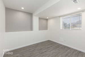 Open room featuring wood-finish flooring, and a window with blinds, recessed lighting