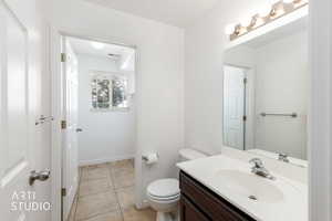 Bathroom featuring a vanity with a white countertop and dark wood-finish cabinetry, a large mirror, and a four-bulb vanity light fixture