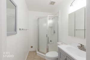 Bathroom featuring a shower stall with frosted glass, a white toilet, and a vanity with a white countertop and gray cabinetry