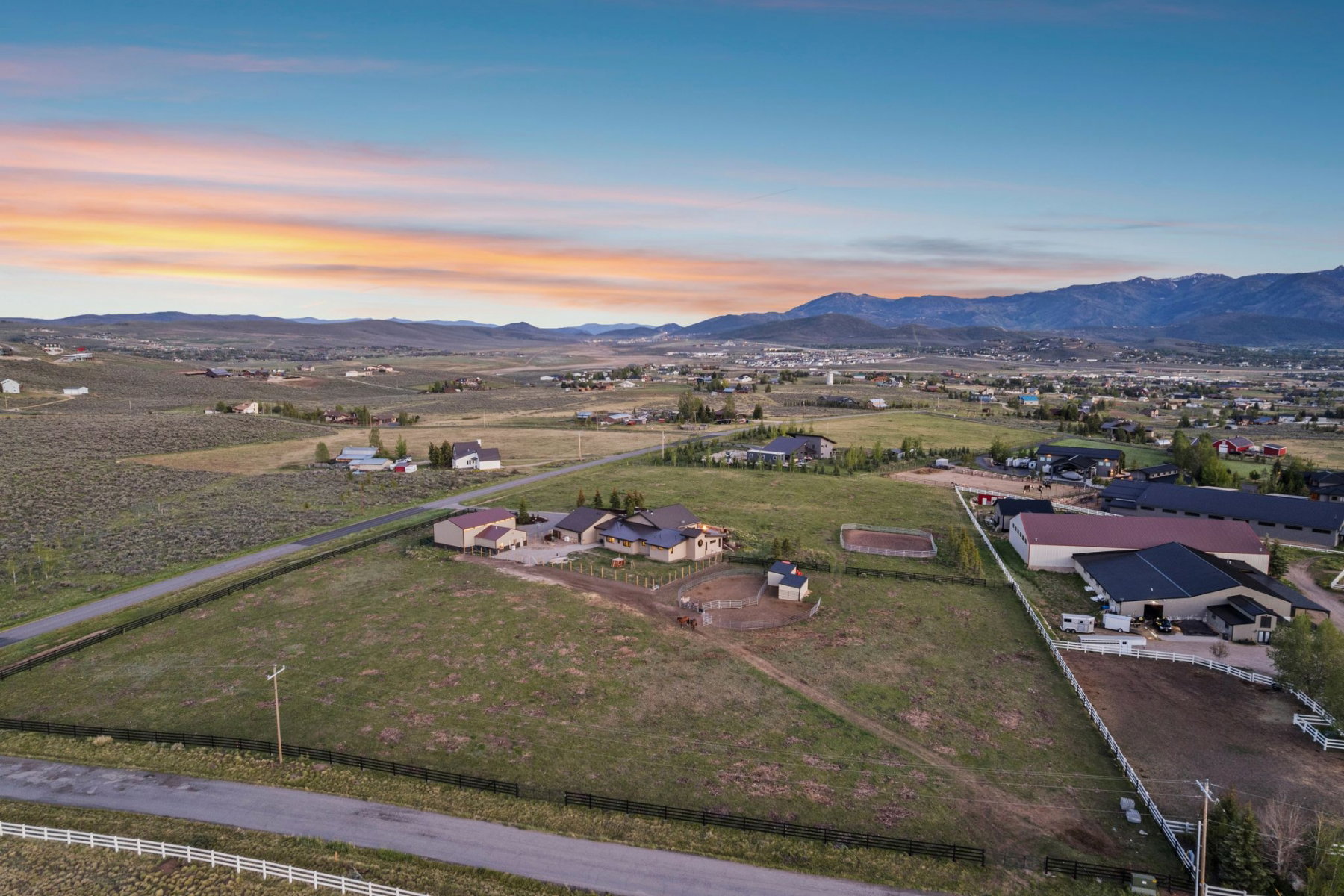Expansive rural property featuring multiple structures, a fenced arena, and a large open field