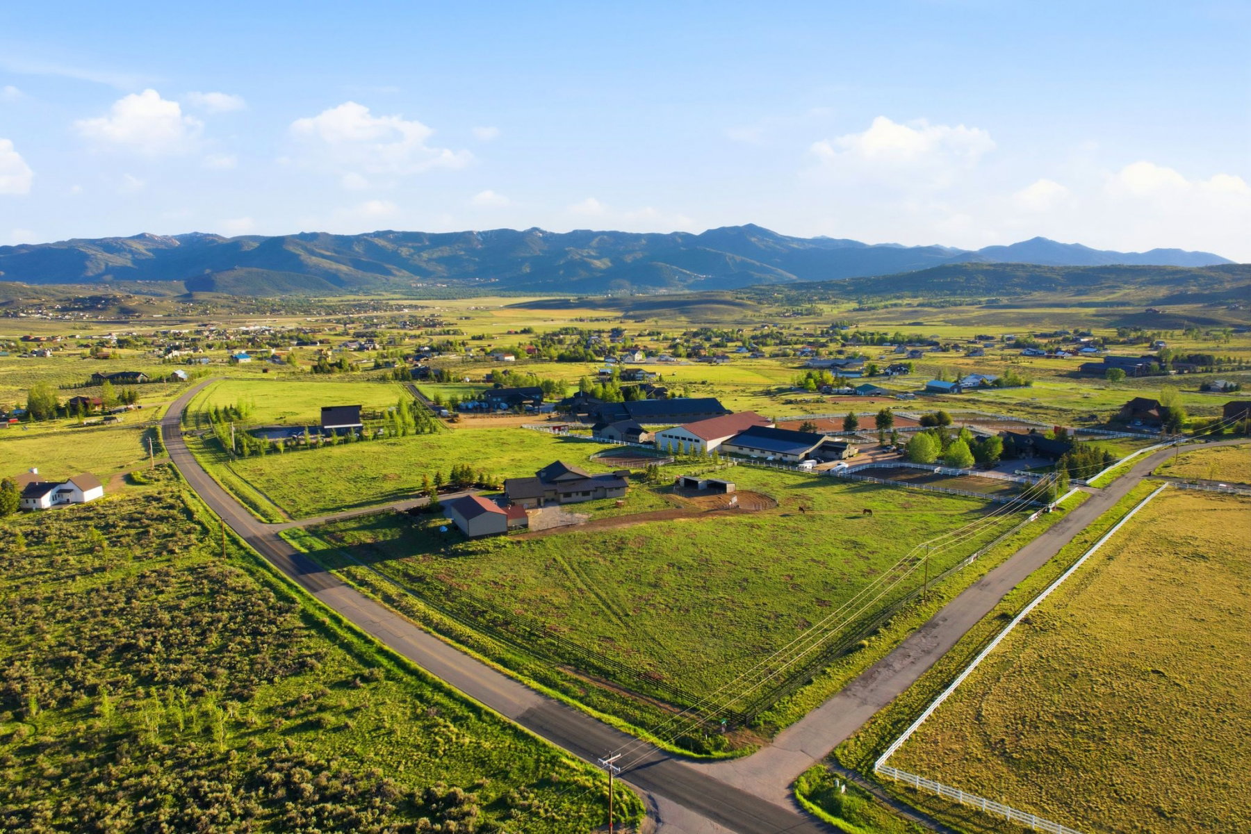Expansive property featuring verdant green fields, multiple structures, and paved roads
