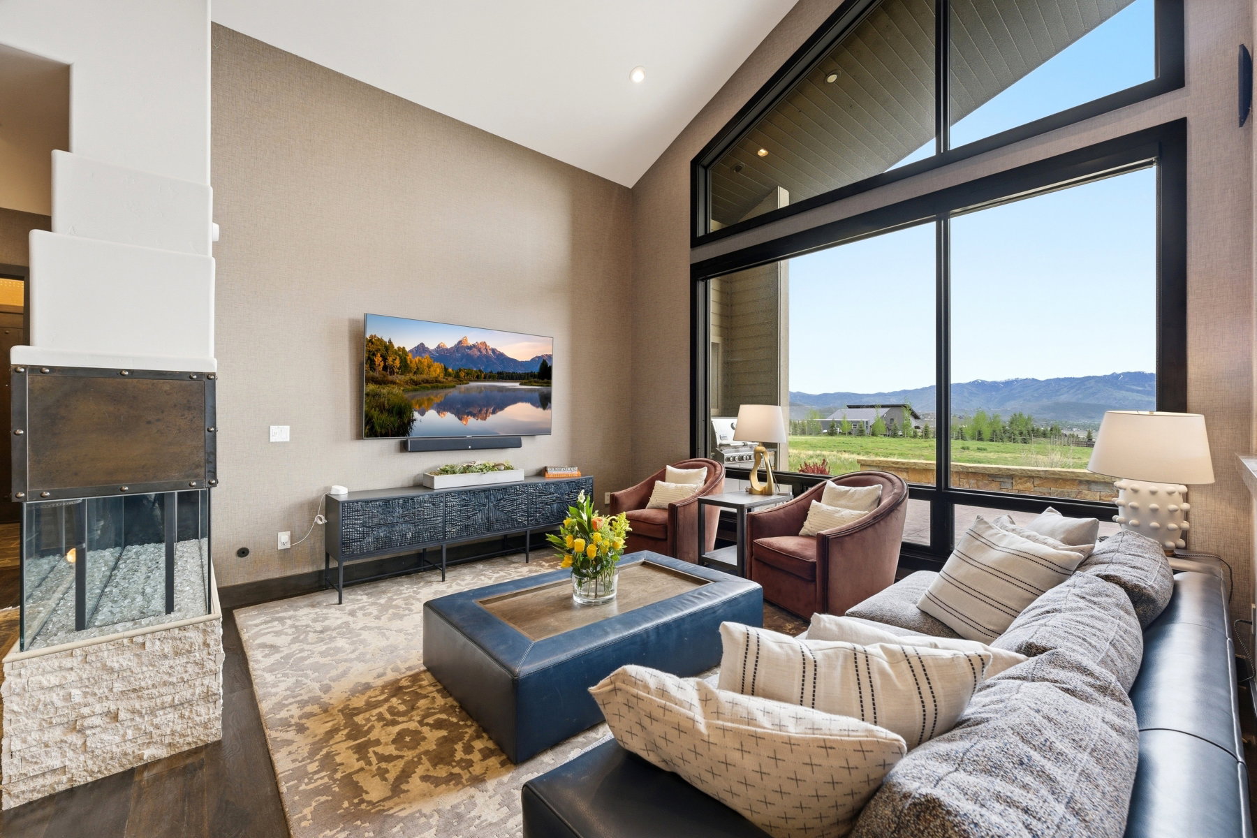Spacious living area featuring a vaulted ceiling and expansive floor-to-ceiling windows